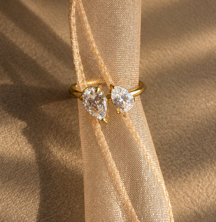 Bague dorée Toi & Moi à deux oxydes de zirconium taille poire sur un ruban champagne.