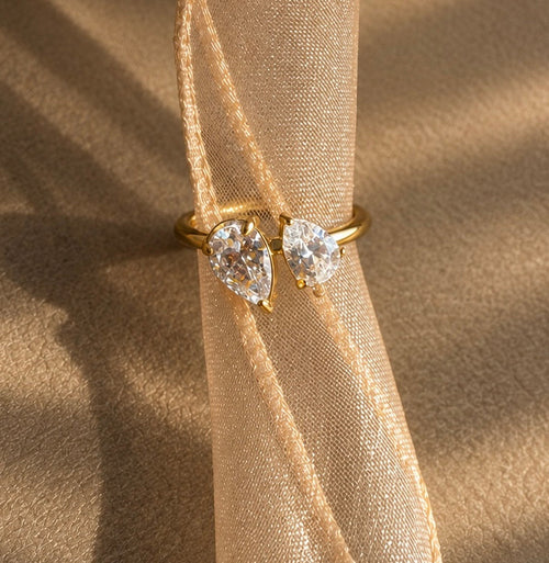 Bague dorée Toi & Moi à deux oxydes de zirconium taille poire sur un ruban champagne.